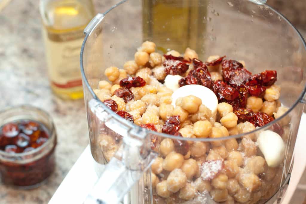 a food processor with chickpeas and sun-dried tomatoes.