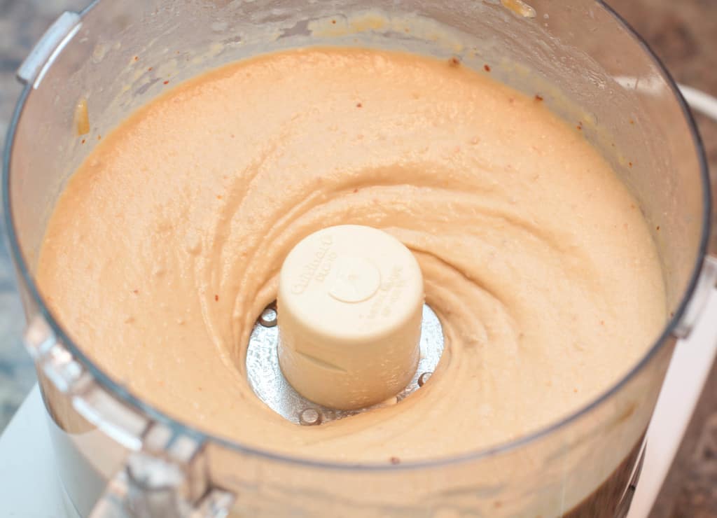 a food processor with blended hummus.