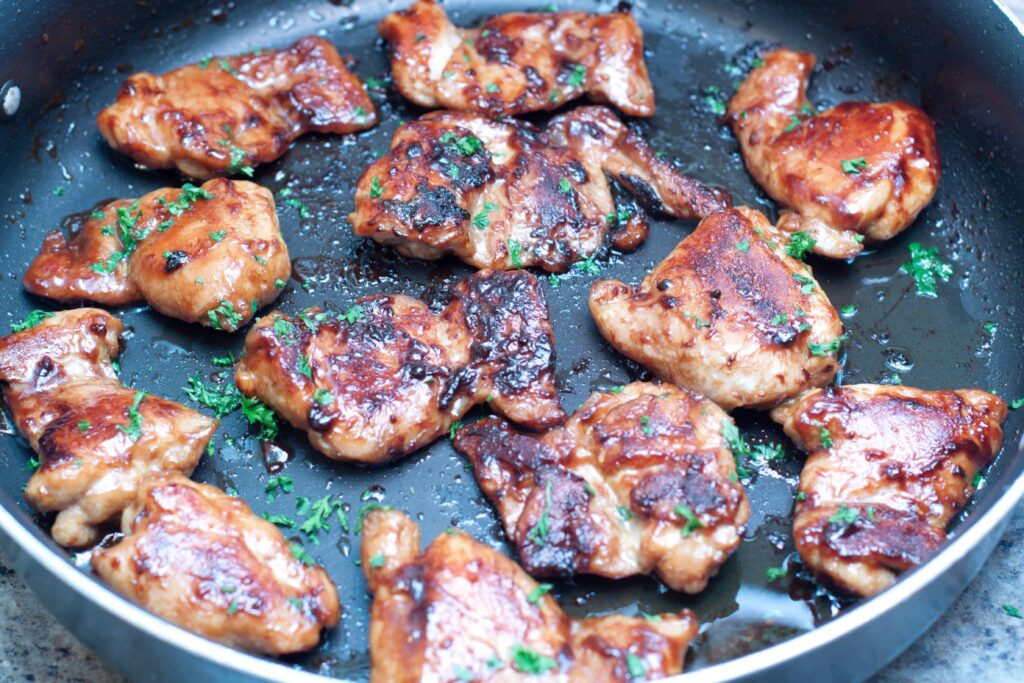cooked boneless chicken thighs in a pan glazed in soy and maple.