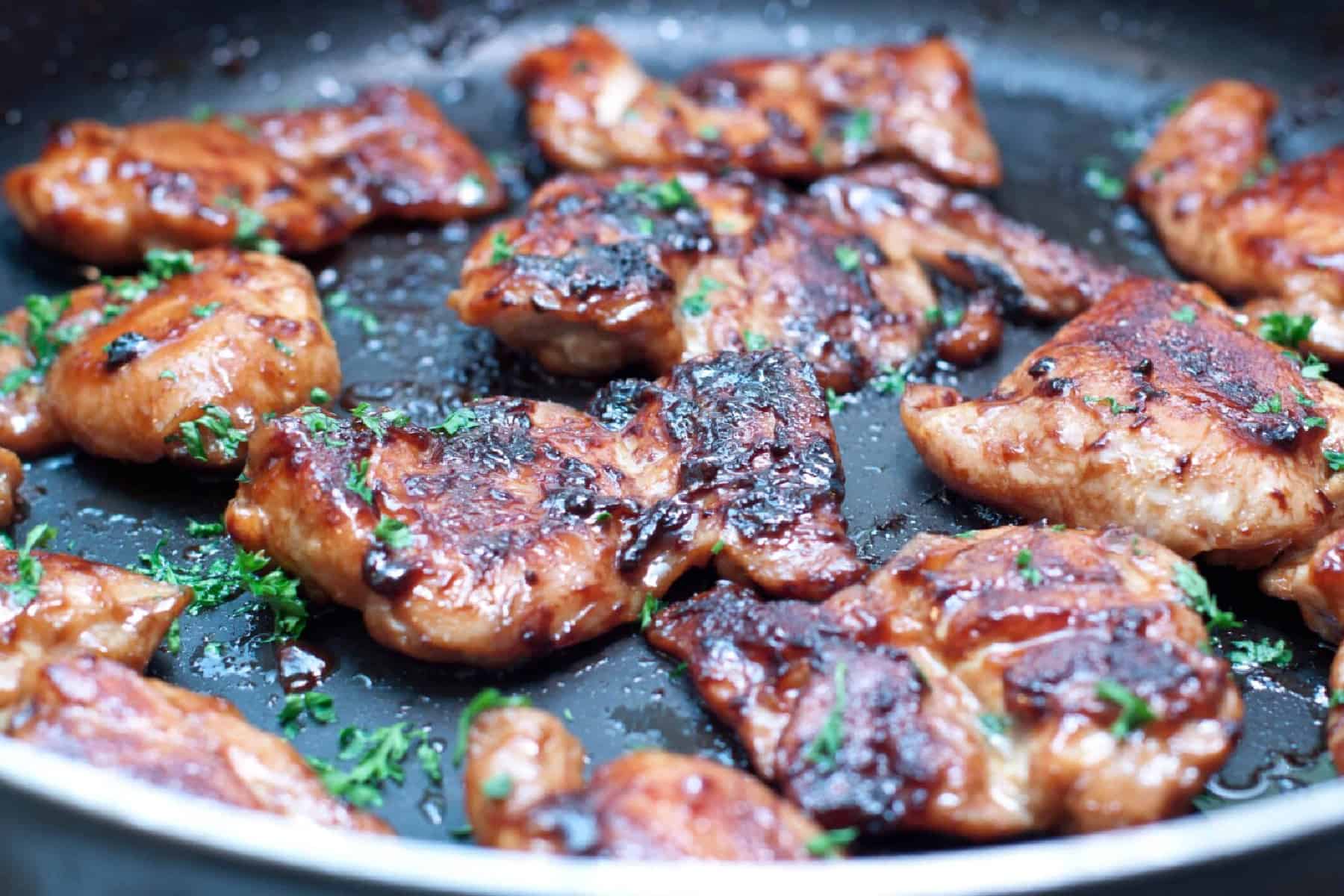 glazed chicken thighs in a pan.