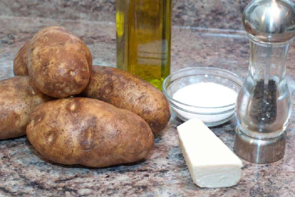 potatoes, olive oil, salt, parm, pepper on a counter.