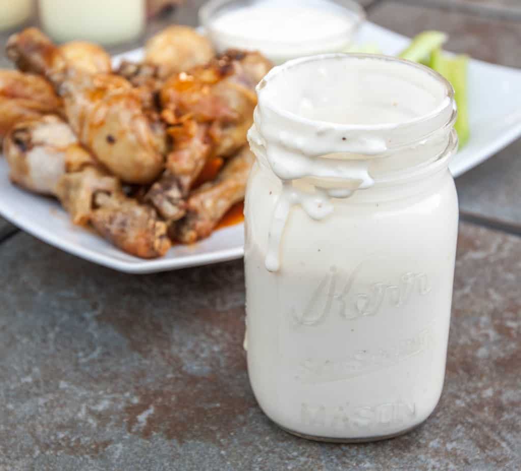 a mason jar of blue cheese in front of a plate of legs.