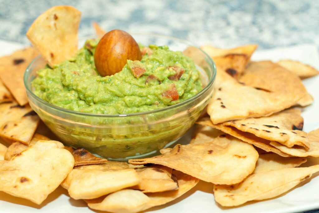 a plate of homemade chips and a bowl of guacamole.