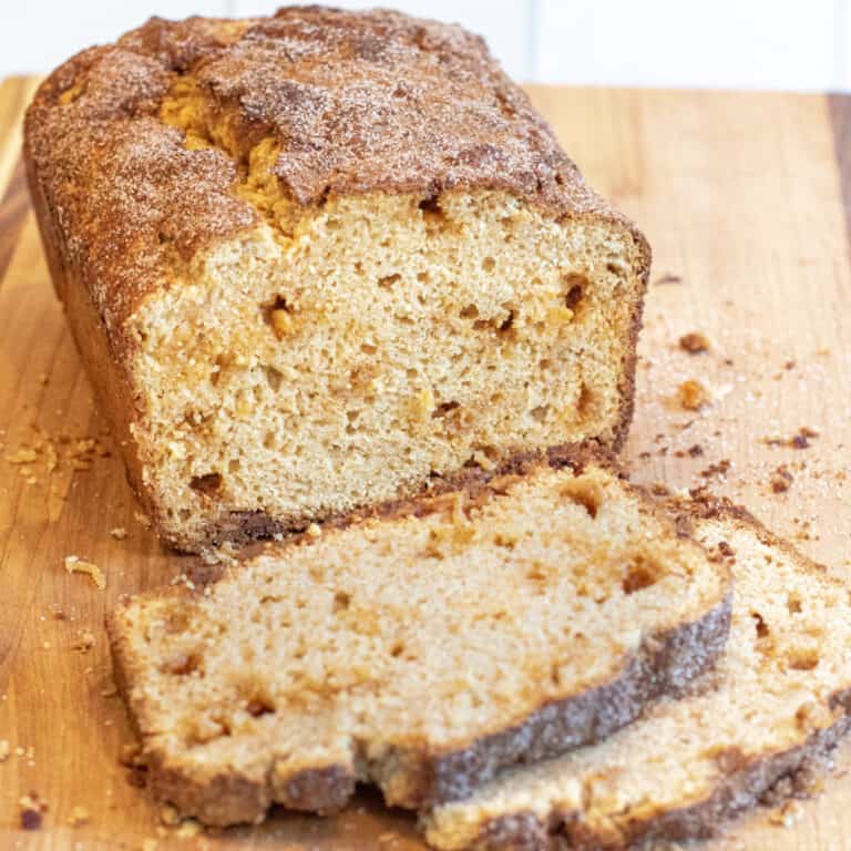 a loaf of sweet bread topped with cinnamon and sugar and slices cut out on next to it.