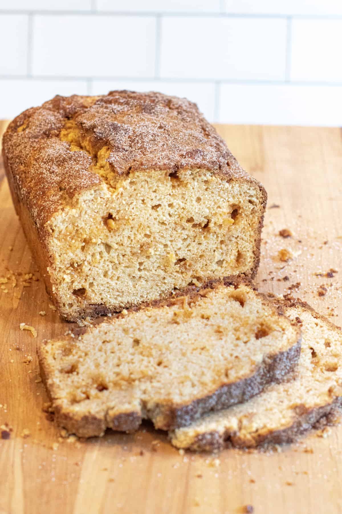 a loaf of snickerdoodle bread on a cutting board with two slices cut off.
