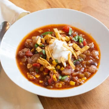 a bowl of taco soup with sour cream and tortilla strips.