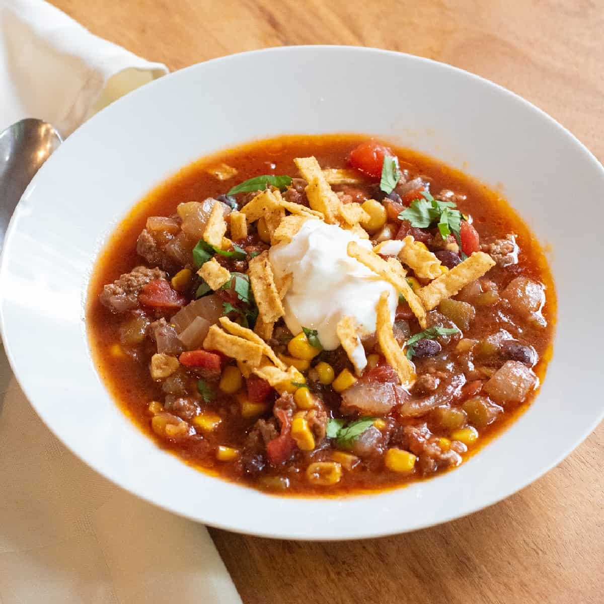 a bowl of taco soup with sour cream and tortilla strips.