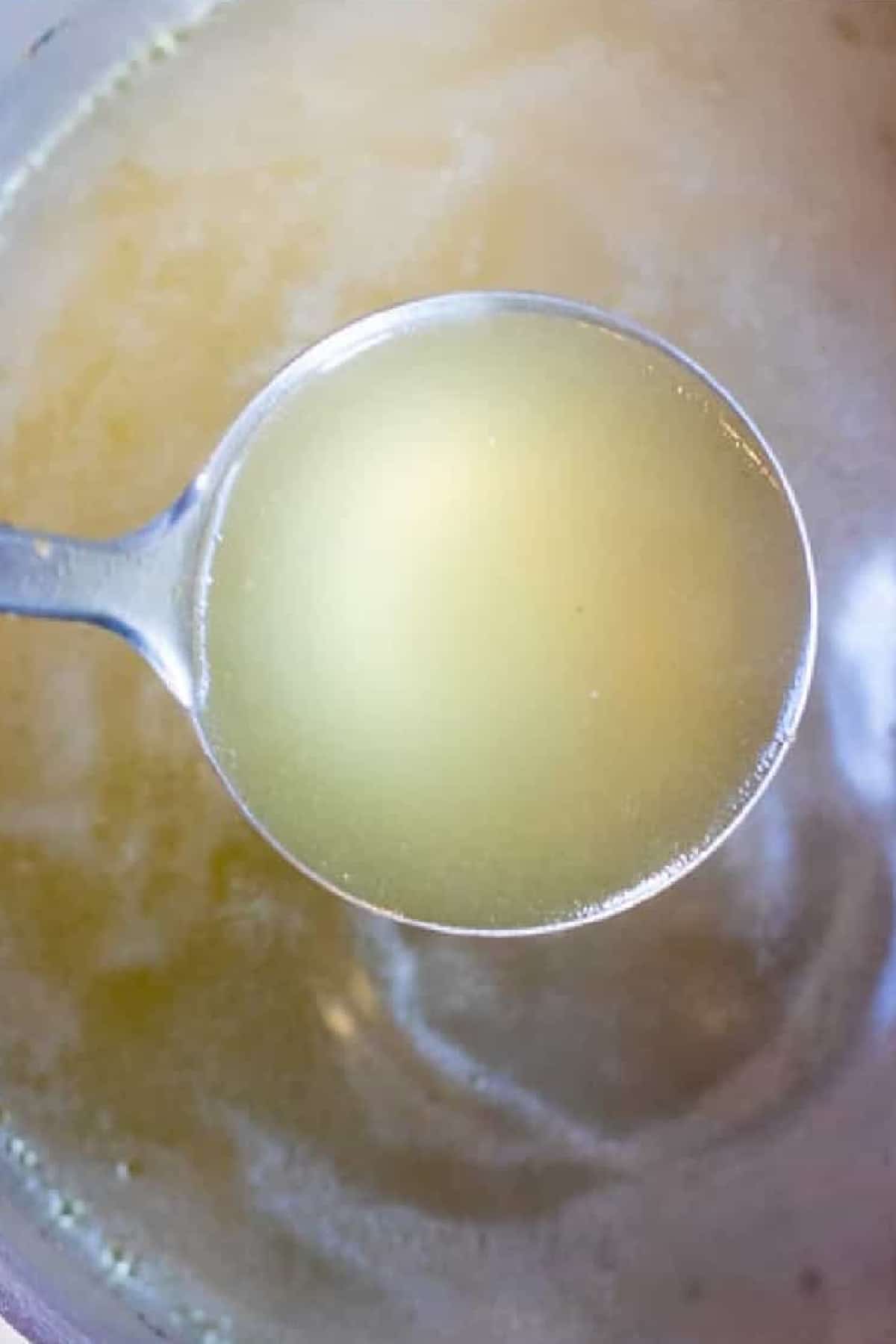 a pot of stock with a ladle of clarified stock. 