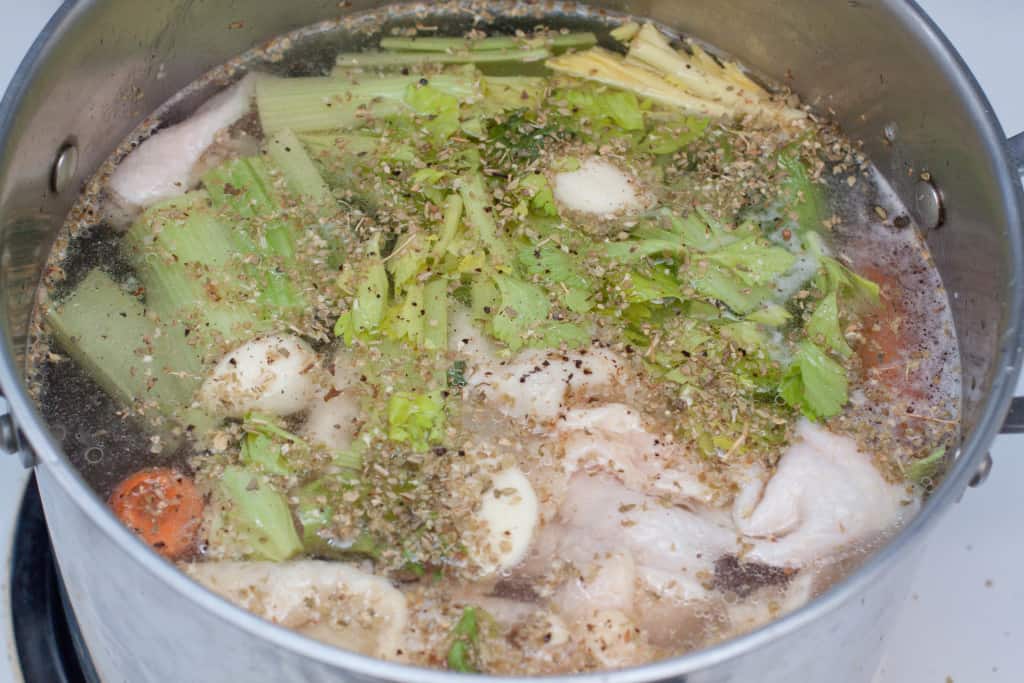 a stock pot of raw chicken, celery, and spices. 