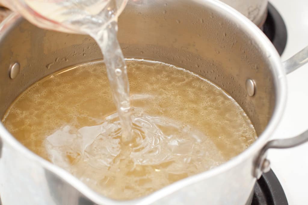 egg white and water being poured into a pot of stock.
