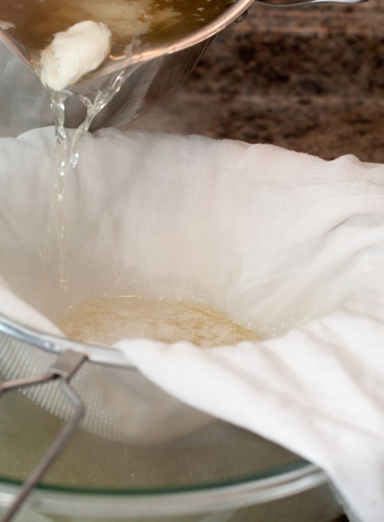 Stock with cooked egg whites being poured into a cheese cloth.