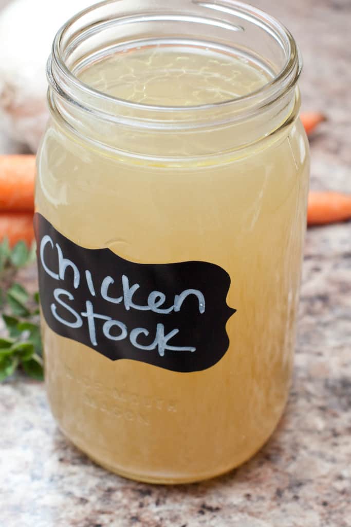 a mason jar of clarified chicken stock with a black label.