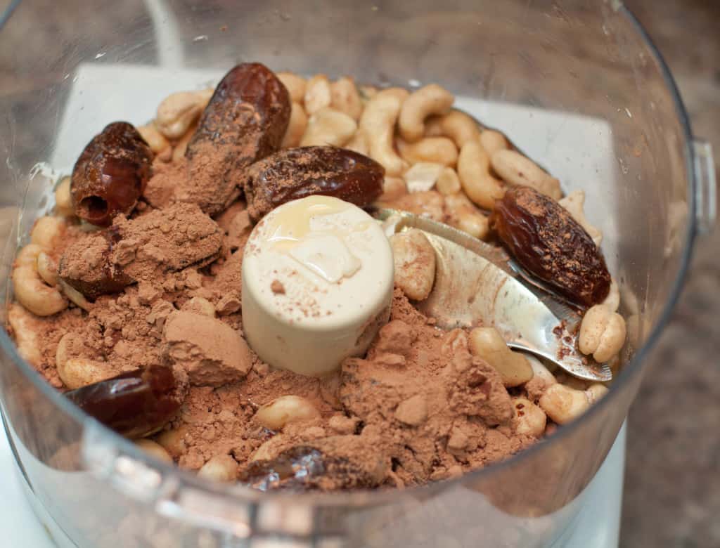 bowl of food processor with cashews, dates, and cacao