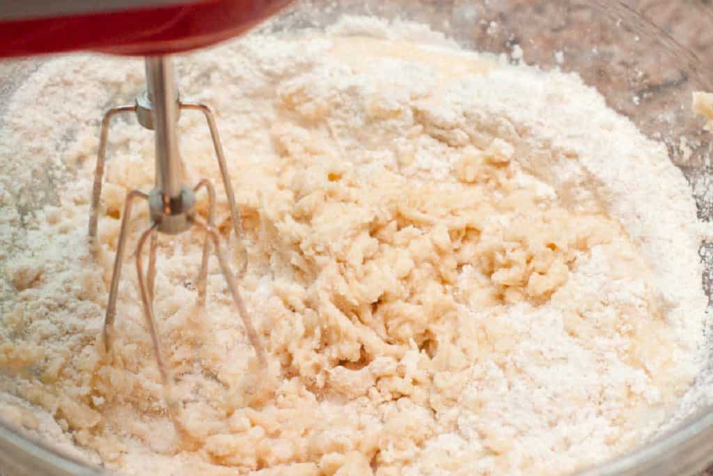 a hand mixer mixing dough in a bowl.