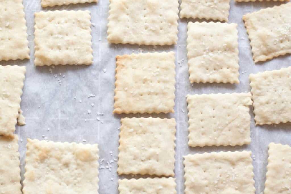 baked saltine crackers lined up on parchment paper