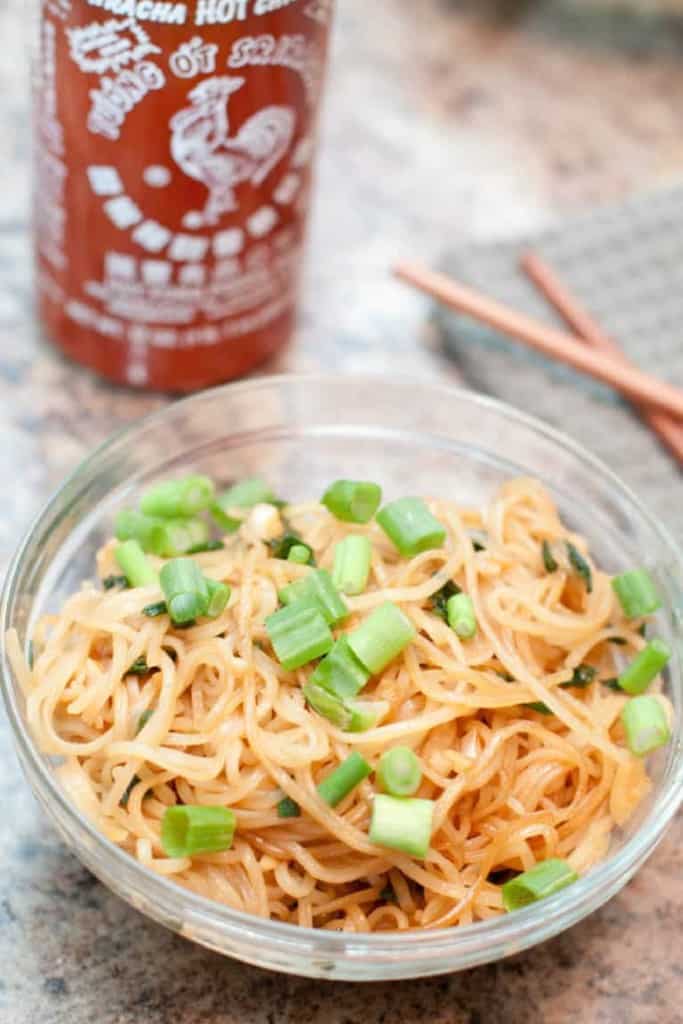 a bowl of garlic fried noodles topped with green onions.