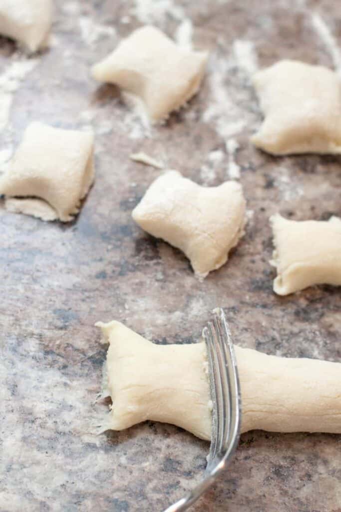 a fork cutting gnocchi.