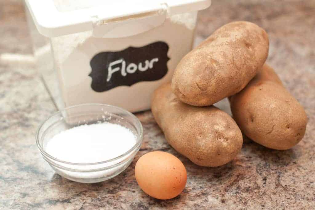 flour, potatoes, egg, and salt on a counter.