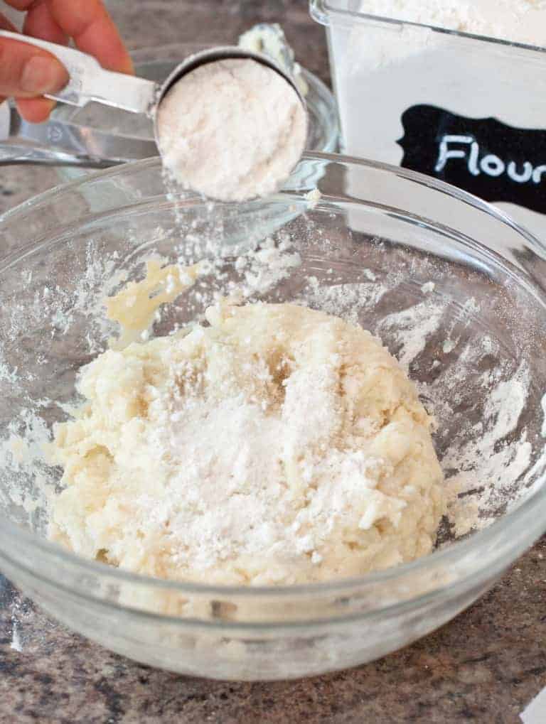 a bowl of dough with flour being poured in.