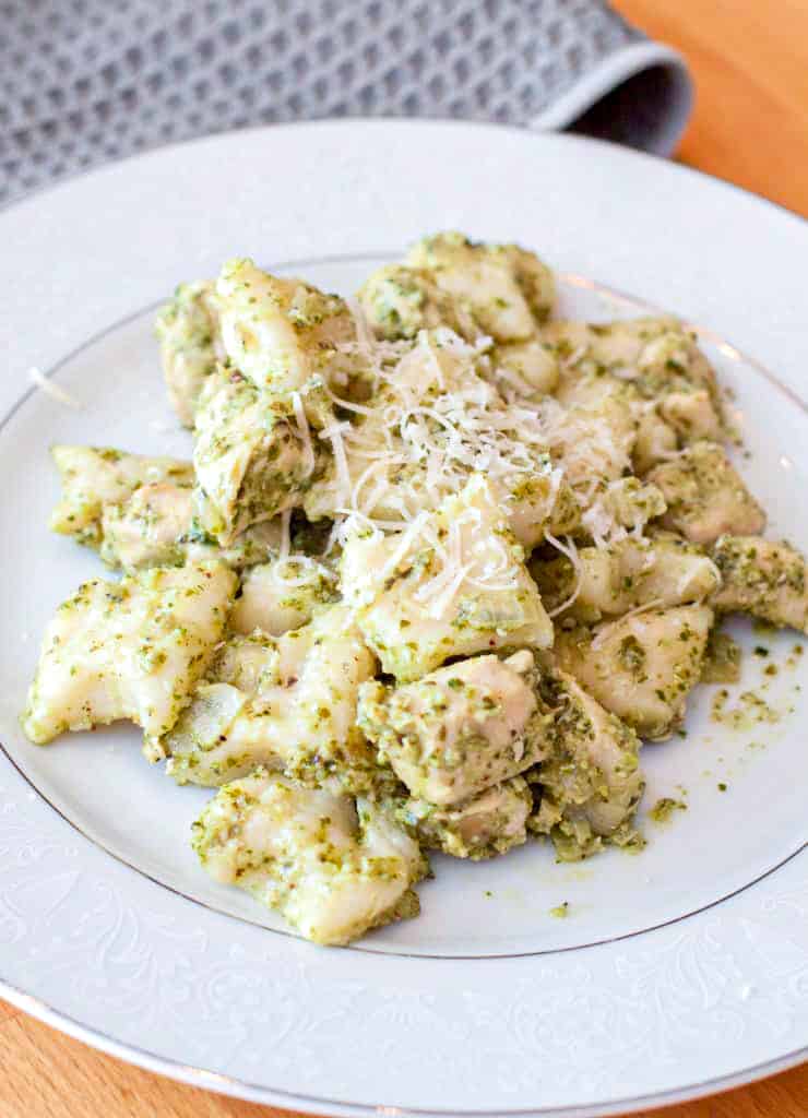 a plate of cooked gnocchi in pesto with cheese.