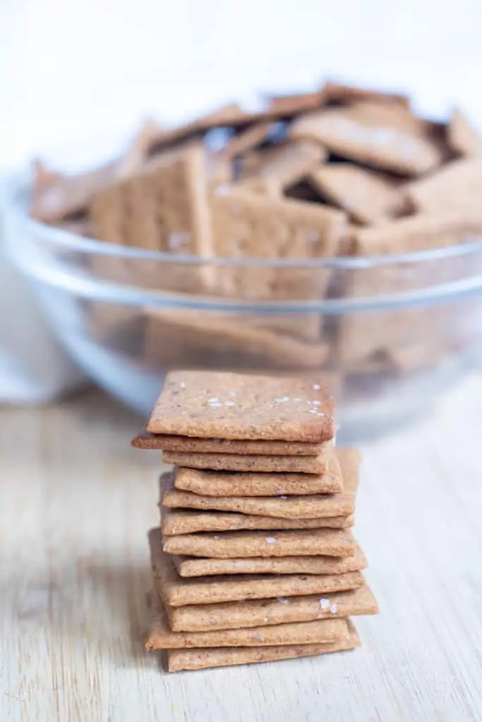 stacked crackers in front of a bowl of crackers.