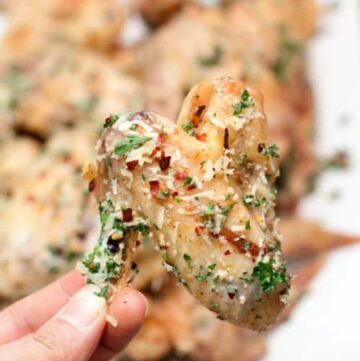 parmesan garlic baked chicken wing held in the air