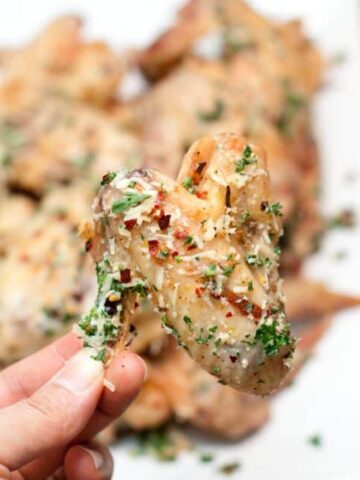 parmesan garlic baked chicken wing held in the air