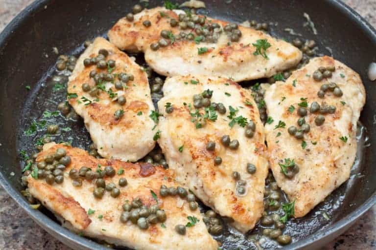 a pan of cooked chicken topped with capers