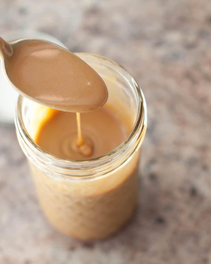 a spoon of caramel sauce over a mason jar 