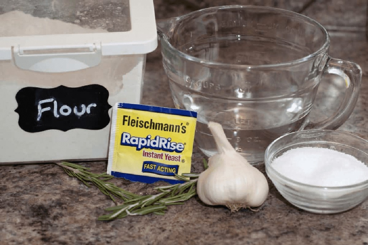 flour, yeast, garlic, salt, and water on a counter.