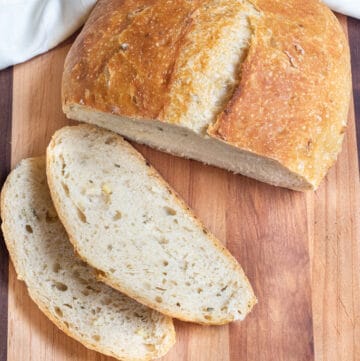 a loaf of bread sliced on a cutting board.