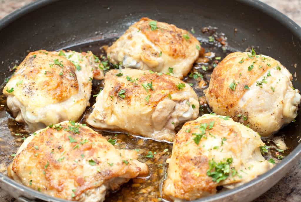 skin on baked chicken thighs in a pan.