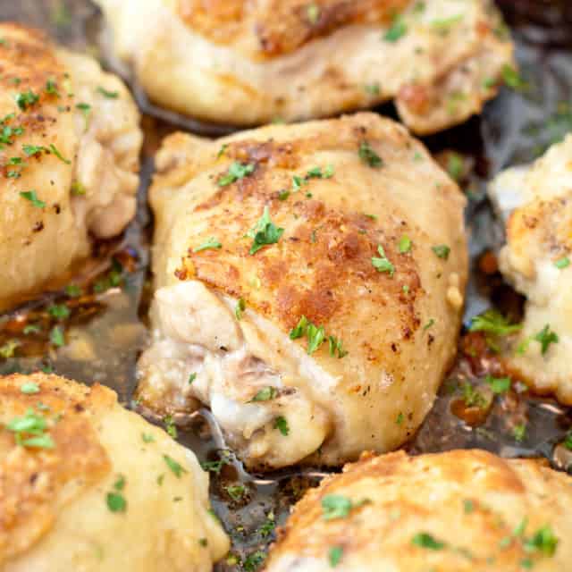 skin on baked chicken thighs in a pan.