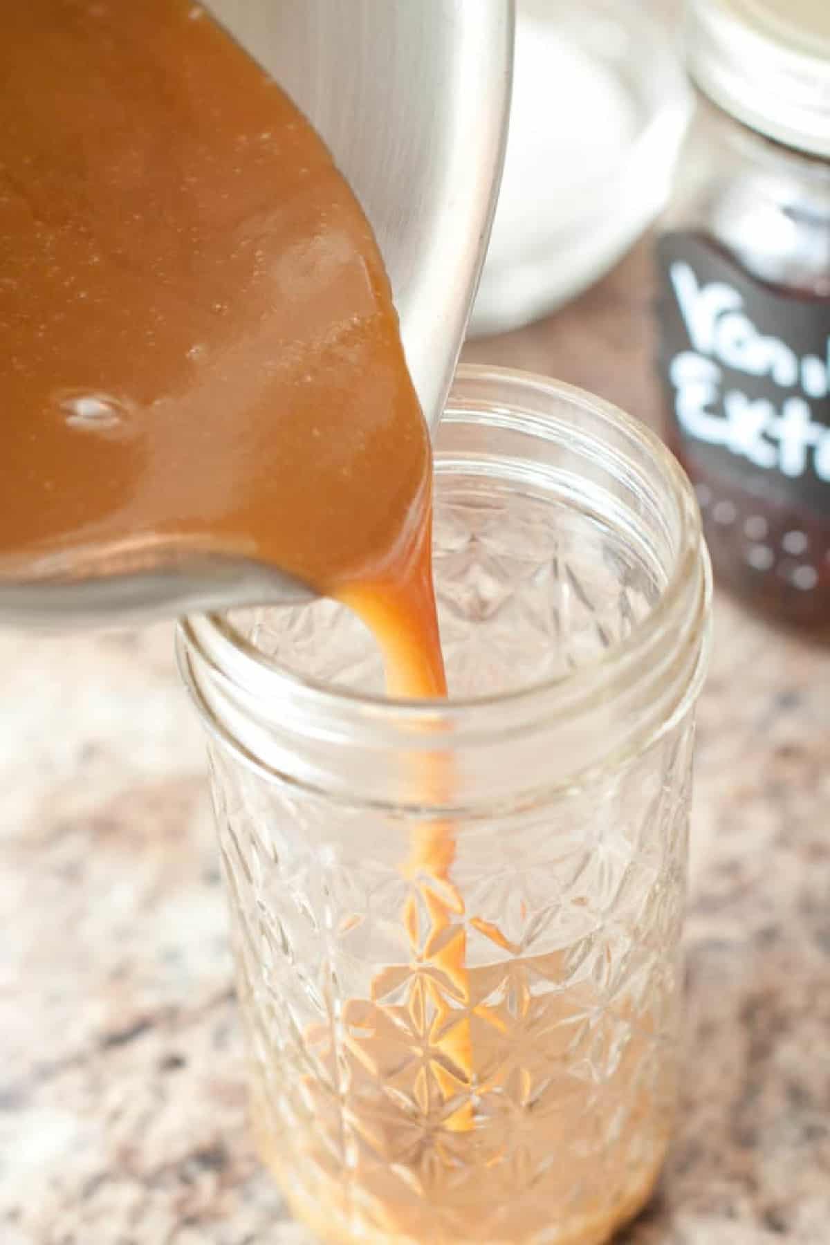 caramel being poured from a pot into a mason jar.