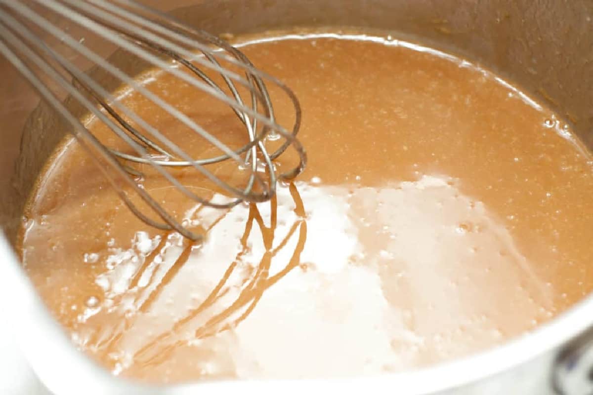 a whisk in a pot of caramel sauce.