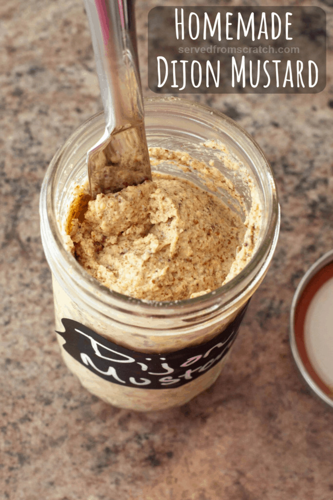 overhead of an open jar of dijon mustard with Pinterest pin text.