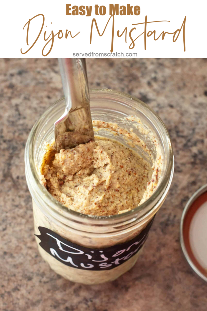 homemade Dijon mustard in a mason jar with knife with Pinterest pin text.