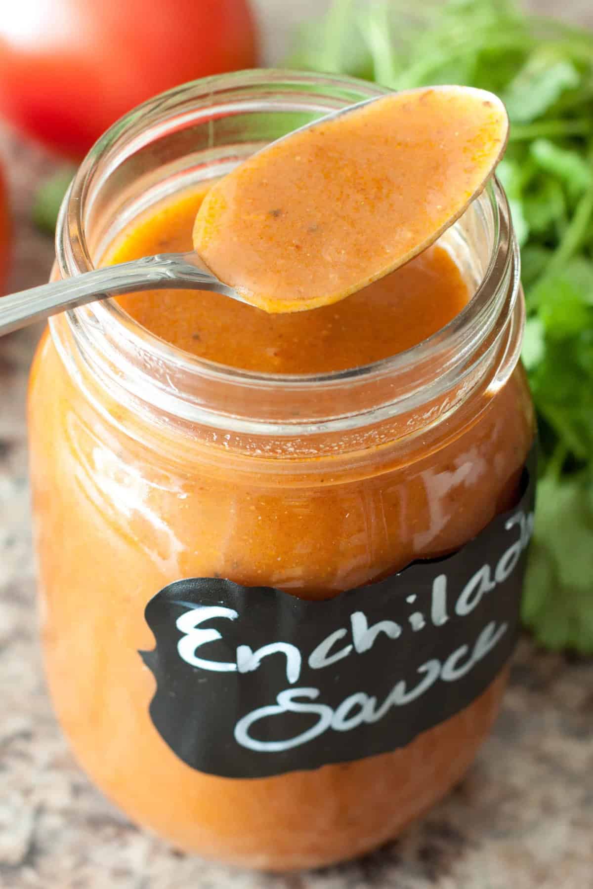 an open labeled jar of enchilada sauce with a spoon.