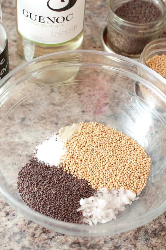 a bowl with mustard seeds, diced shallots, and salt.