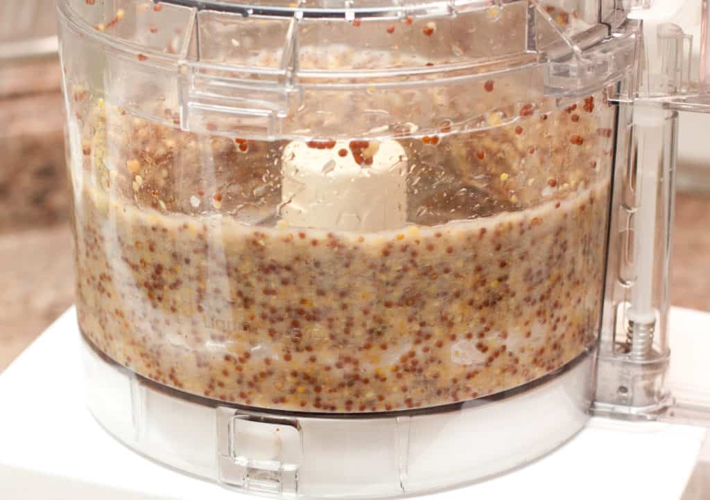 food processor with mustard seeds blending mustard.