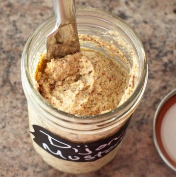 homemade Dijon mustard in a mason jar with knife.