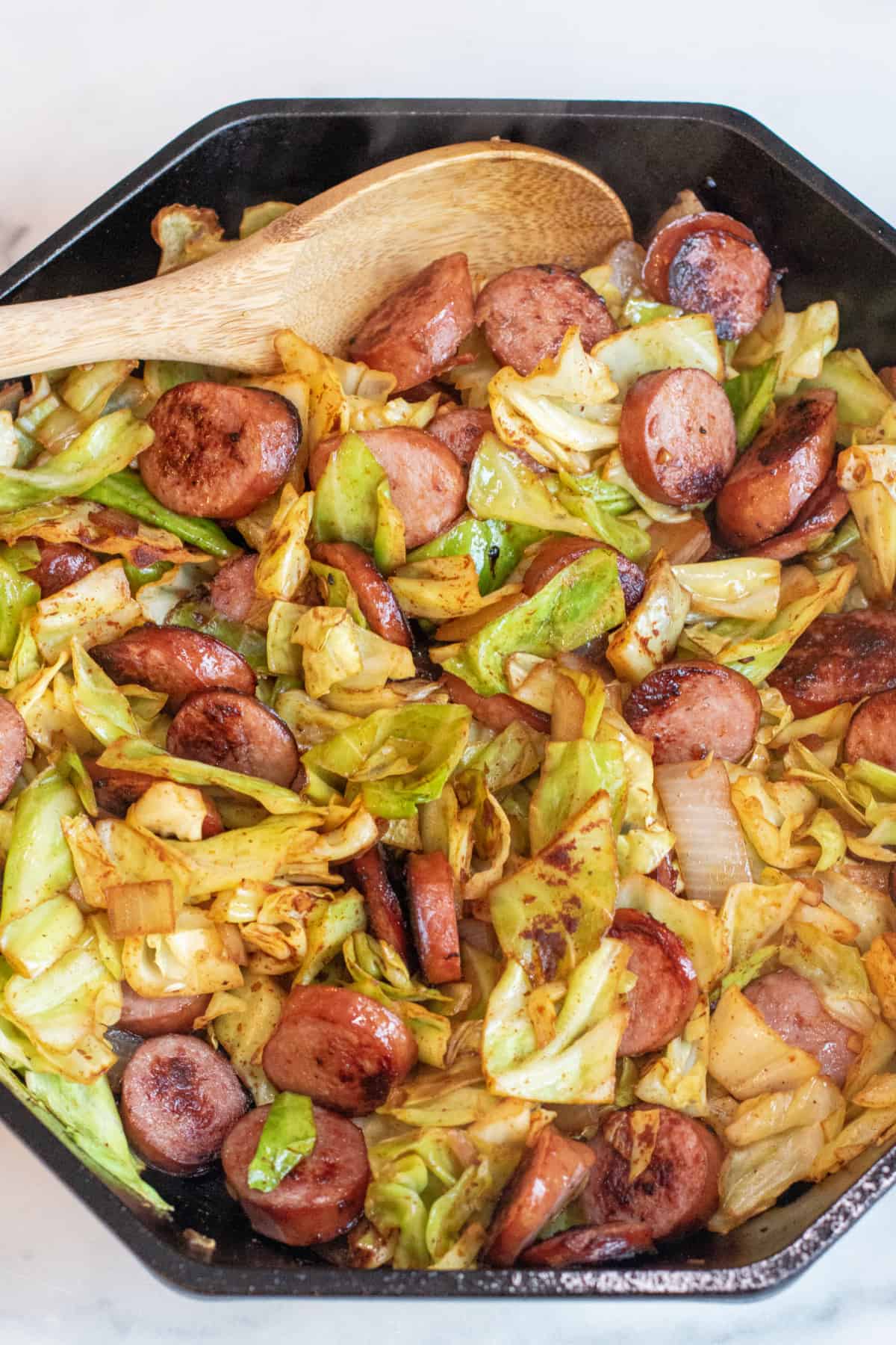 overhead of large pan with cooked kielbasa and cabbage.