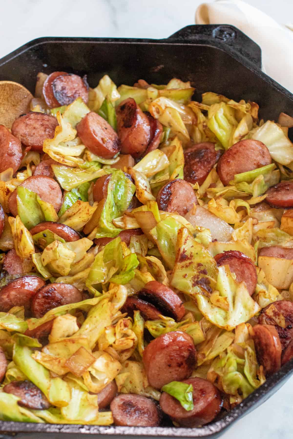 overhead of large pan with cooked kielbasa and cabbage.