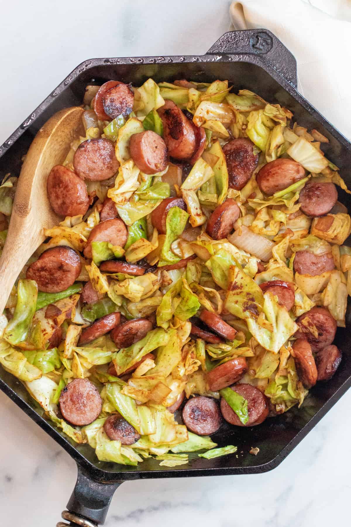 overhead of large pan with cooked kielbasa and cabbage.
