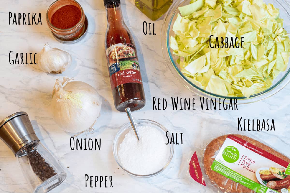 cabbage, red wine vinegar, pepper, onion, kielbasa, garlic, oil, paprika, salt on counter.
