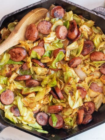 overhead of large pan with cooked kielbasa and cabbage.