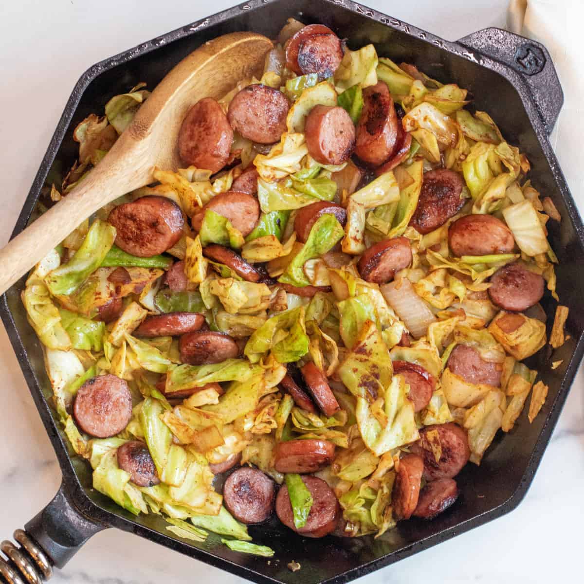 overhead of large pan with cooked kielbasa and cabbage.