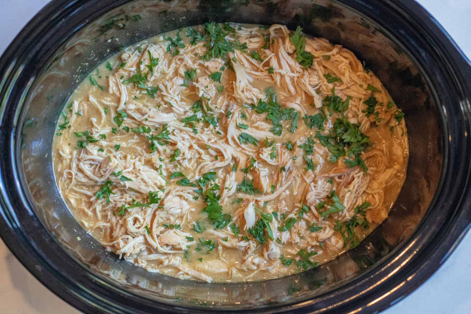 shredded chicken with parsley in a crock pot.