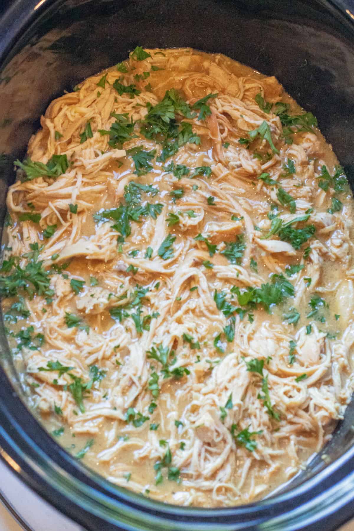 shredded chicken with parsley in a crock pot.