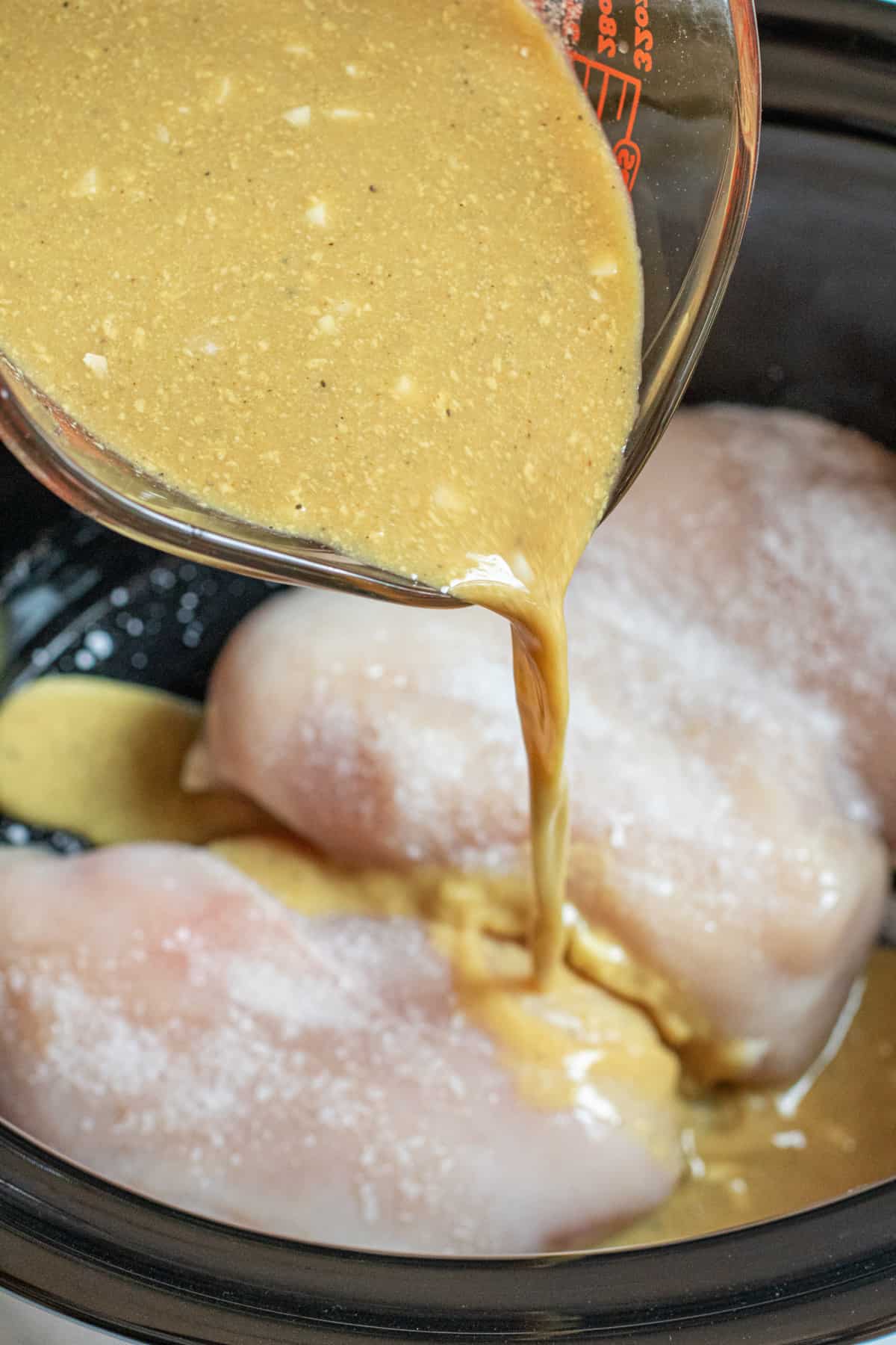 a pyrex of honey mustard sauce being poured on chicken.